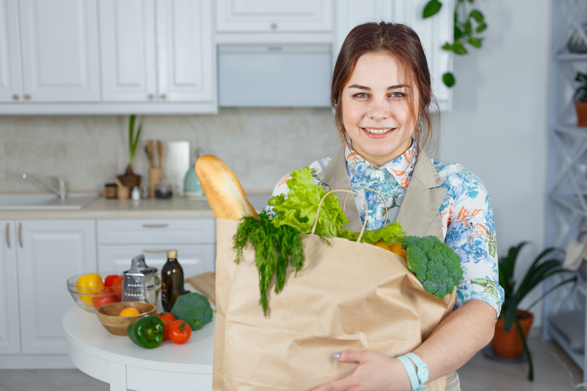 Smiling woman in the kitchen with a bag of groceries shopping